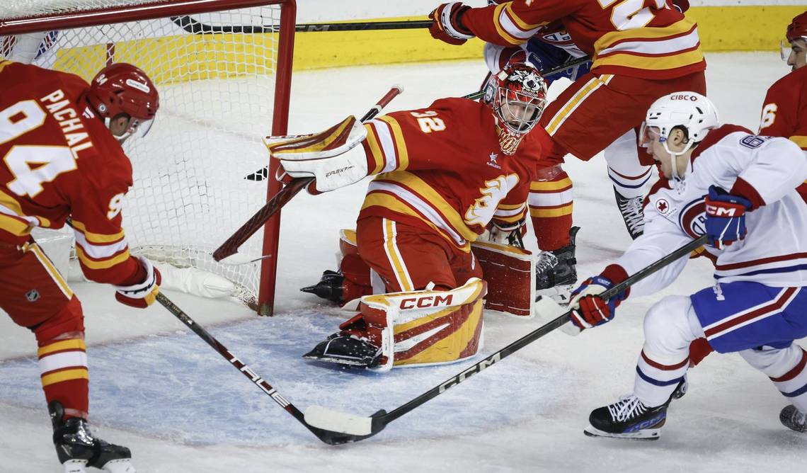 Canadiens’ Owen Beck, right, tries to get at the puck before Calgary Flames’ Brayden Pachal, left, clears it as goalie Dustin Wolf looks on during second period NHL hockey action in Calgary on Saturday, March 8, 2025.